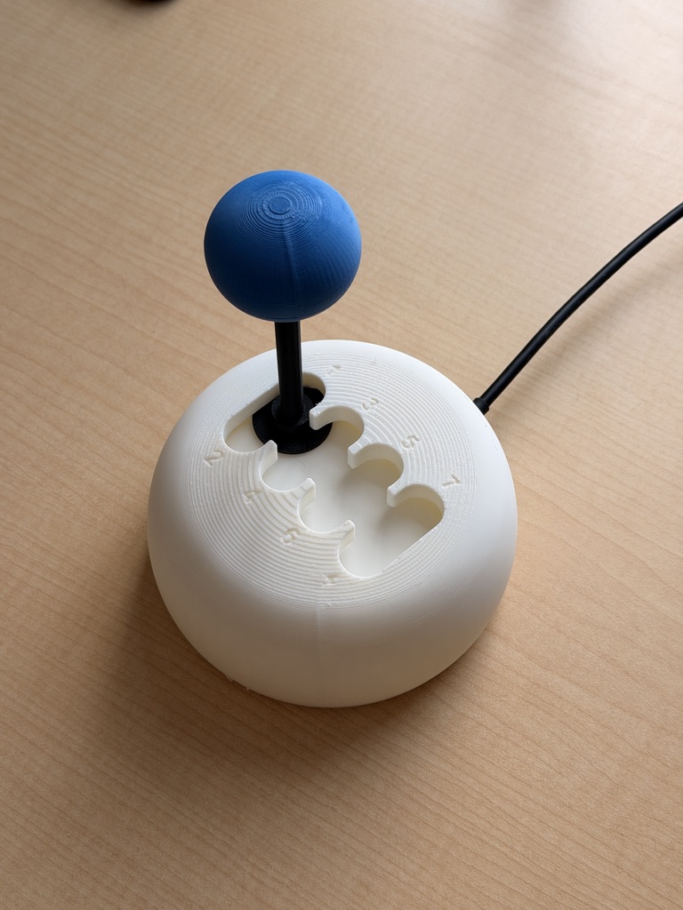 Rshifter prototype V2 with its blue grip and white gated housing on a wooden desk